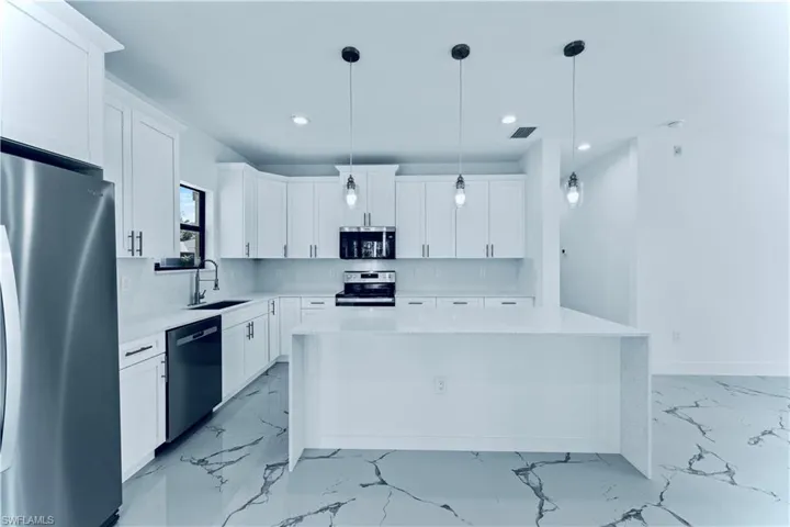 Kitchen with white cabinetry, stainless steel appliances, sink, and a kitchen island