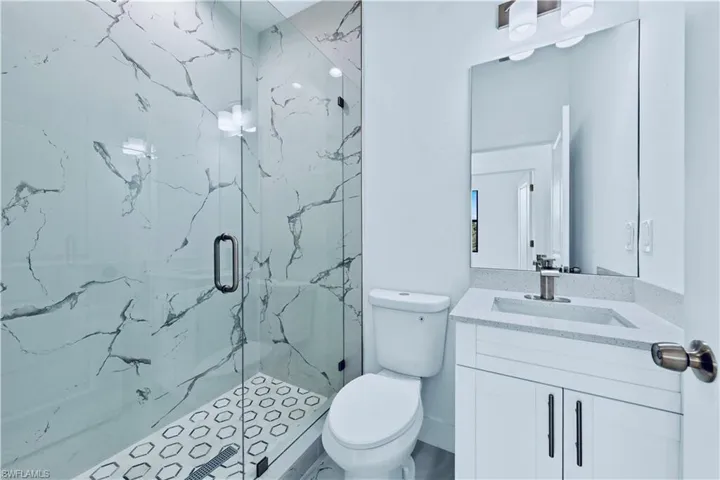 Bathroom with a shower with door, vanity, and toilet