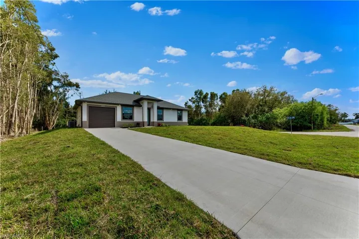 Single story home featuring a garage, cooling unit, and a front lawn