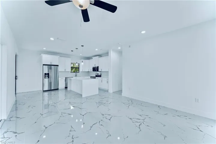 Kitchen featuring decorative light fixtures, white cabinetry, a center island, ceiling fan, and stainless steel appliances