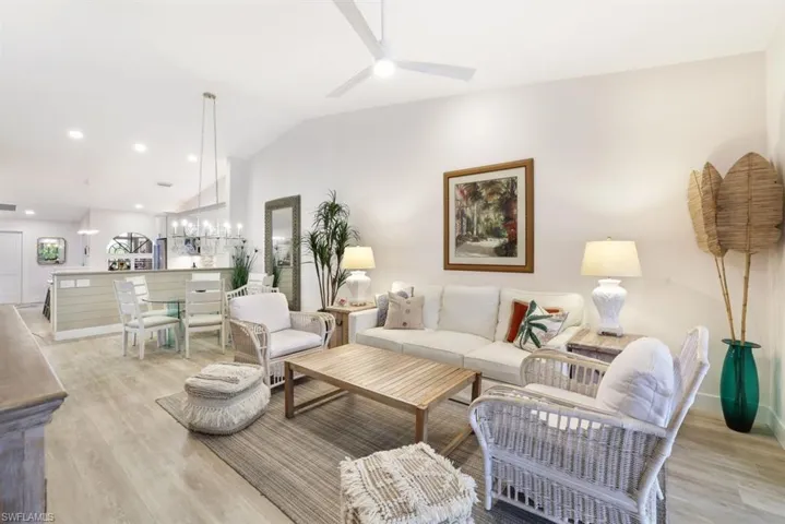 Living room with light hardwood / wood-style flooring, ceiling fan, and vaulted ceiling