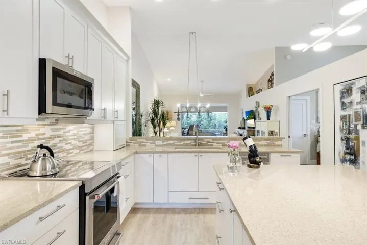 Kitchen with appliances with stainless steel finishes, sink, pendant lighting, and white cabinets