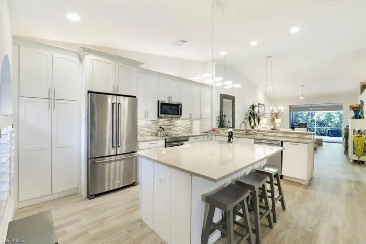 Kitchen with stainless steel appliances, white cabinetry, hanging light fixtures, and a center island