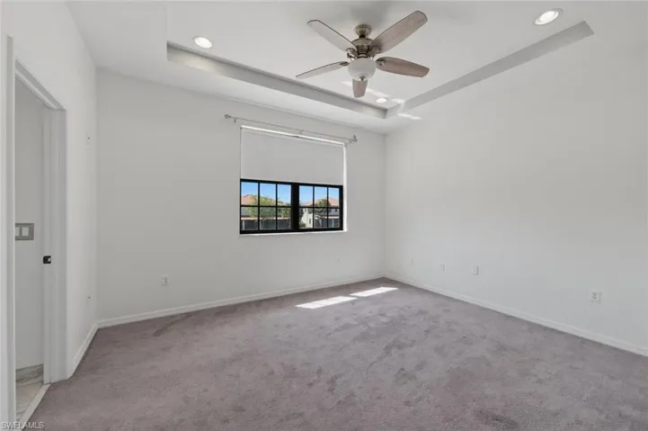 Spare room featuring a raised ceiling, carpet, a ceiling fan, and recessed lighting