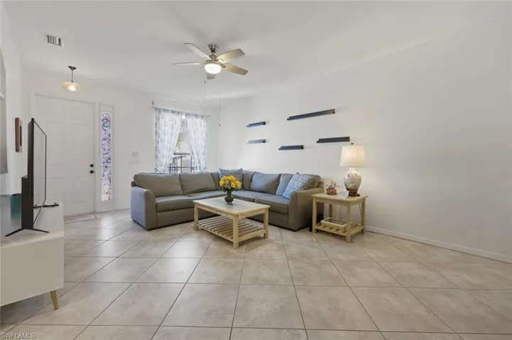 Living area with ceiling fan and light tile patterned floors