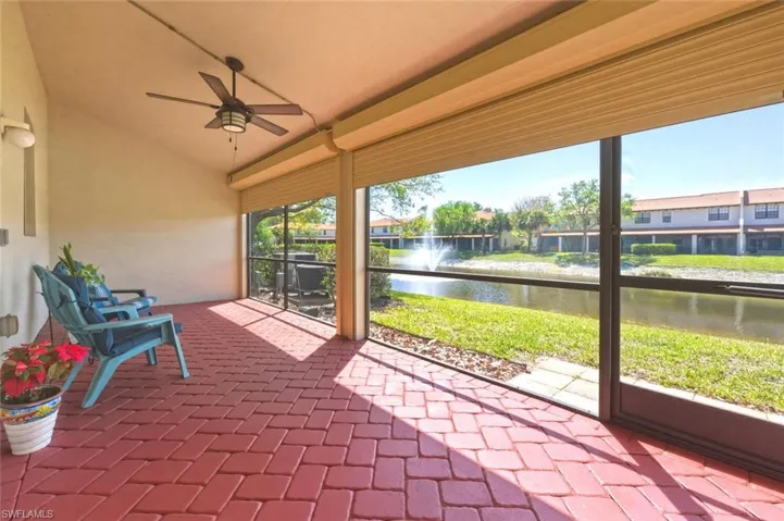 Unfurnished sunroom featuring lofted ceiling, a water view, a ceiling fan, and a patio area