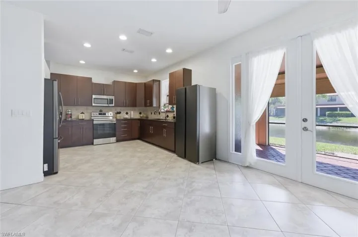 Kitchen with stainless steel appliances, french doors, dark wood finish cabinetry, recessed lighting, and light tile patterned flooring