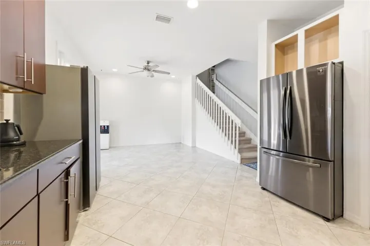 Kitchen featuring freestanding refrigerator, dark stone countertops, recessed lighting, a ceiling fan, and light tile patterned floors