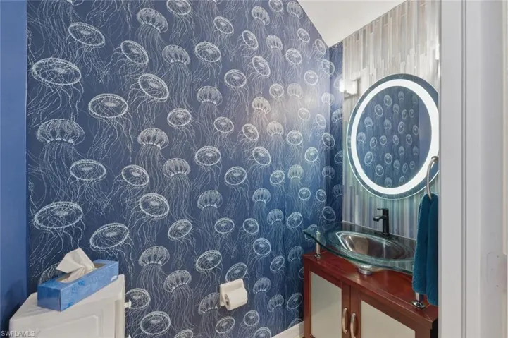 Half bath with vanity and wallpapered walls