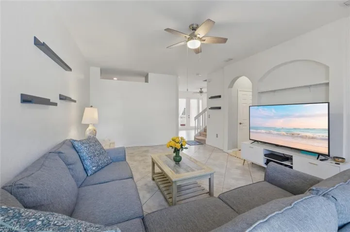 Living room featuring a ceiling fan, arched walkways, and light tile patterned floors