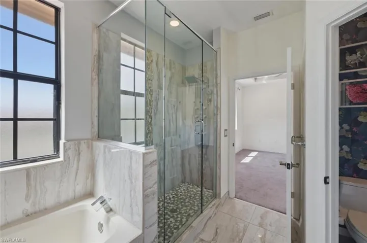Bathroom with a marble finish shower, a garden tub, and light colored carpet