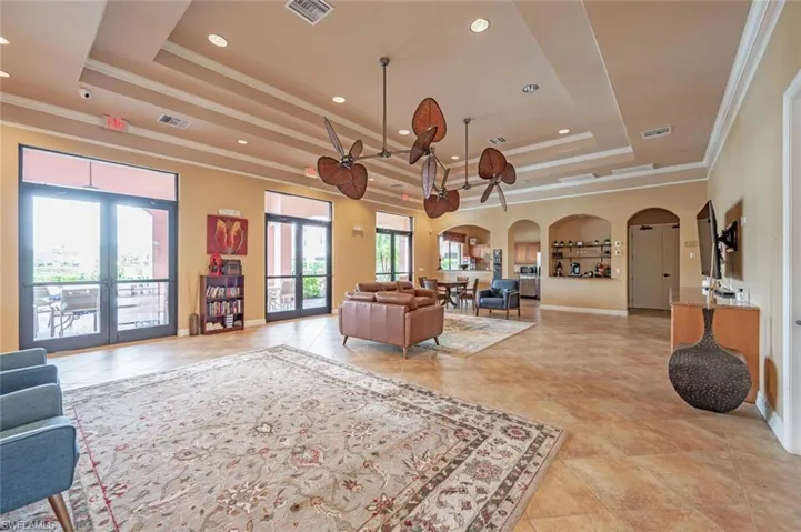 Living room with arched walkways, crown molding, recessed lighting, a raised ceiling, and french doors