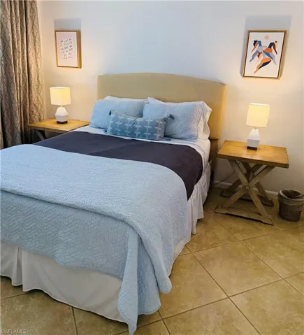 Bedroom featuring a neutral upholstered headboard and light-toned tile flooring