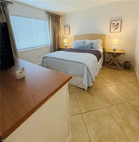 Bedroom featuring neutral-toned tile flooring, light cream wall paint, and a window with blinds
