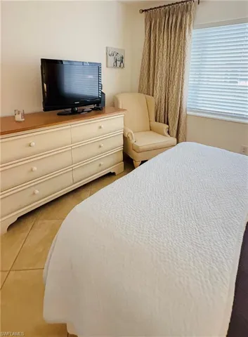 Neutral-toned room featuring light tile flooring and a window with blinds and patterned drapes