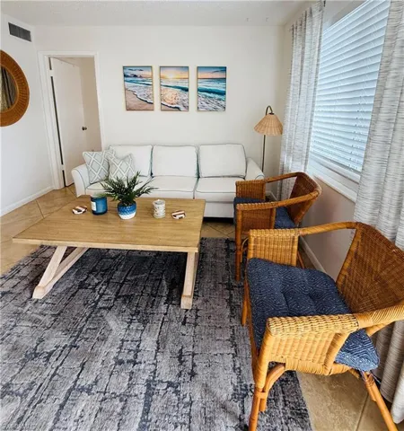 Spacious living area featuring tile flooring, a large window with horizontal blinds and drapery, and a neutral wall color