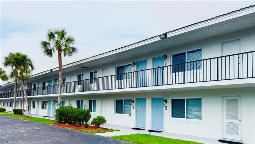 White exterior with light blue unit entry doors and black iron balcony railings