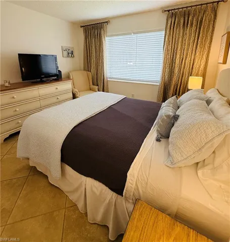 Room featuring ceramic tile flooring, window with blinds, and decorative curtain rods