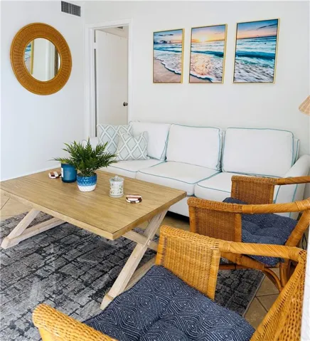 Lounge area featuring a light wood-finish coffee table, white walls, and tiled flooring