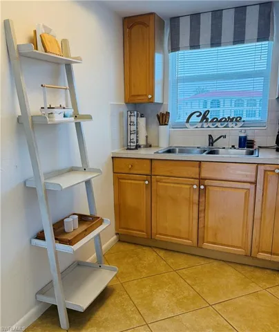 Kitchen featuring wood cabinetry, a double basin stainless steel sink, and light-toned countertops