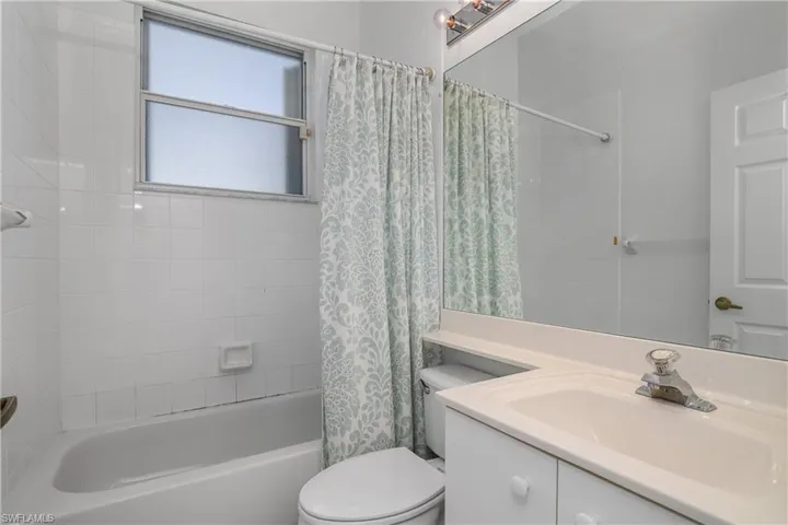 Full bathroom with shower / bathtub combination with curtain, toilet, and vanity