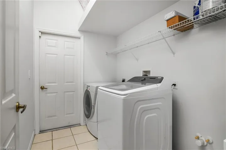 Clothes washing area featuring washer and dryer and light tile patterned floors