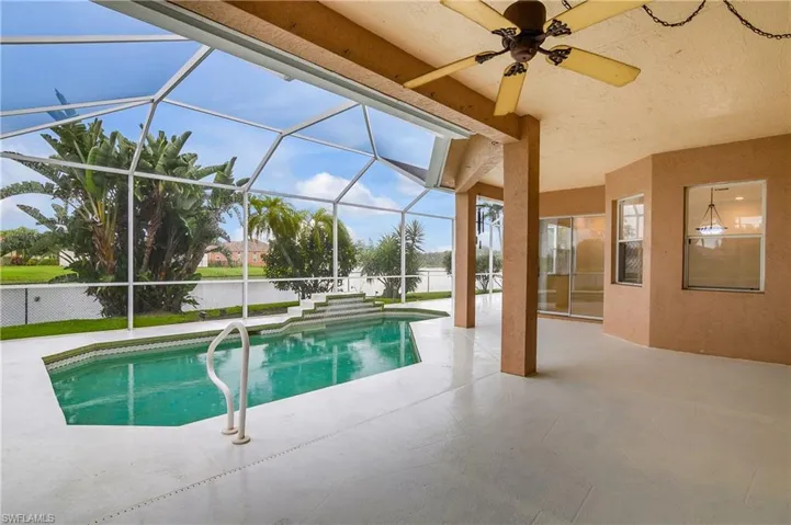View of pool featuring a patio area, ceiling fan, and glass enclosure