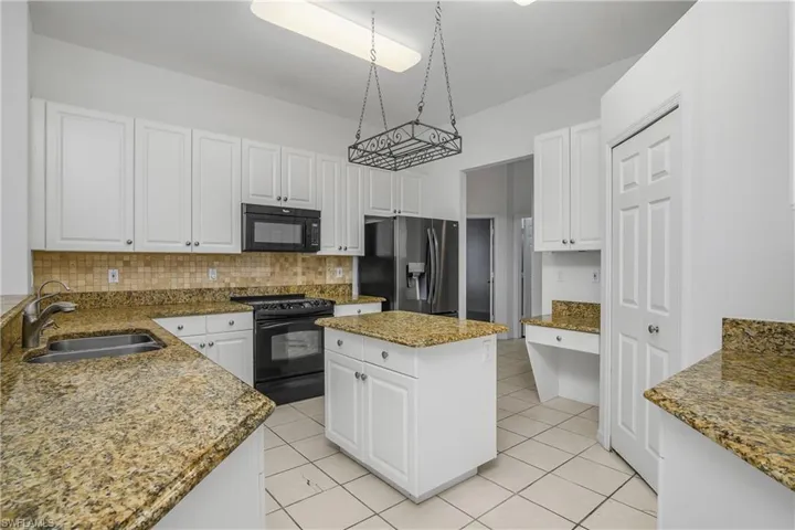 Kitchen featuring black appliances, decorative backsplash, sink, a kitchen island, and light tile patterned floors