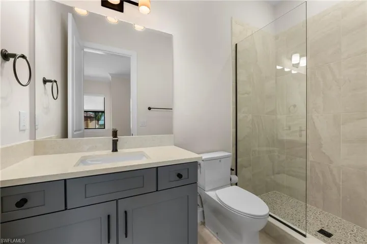 Bathroom with a tile shower, toilet, and vanity