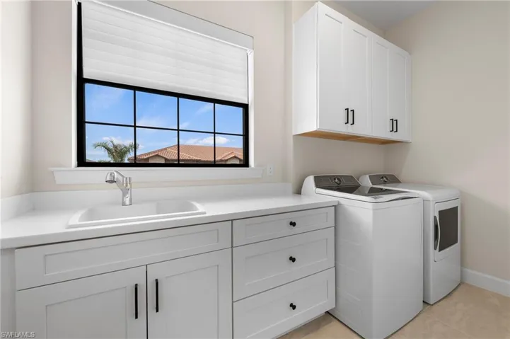 Washroom with baseboards, separate washer and dryer, cabinet space, and a sink