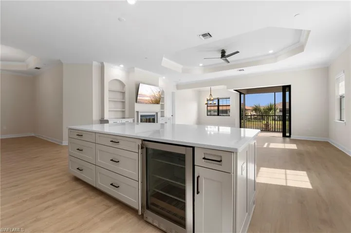 Kitchen featuring a tray ceiling, open floor plan, visible vents, and wine cooler