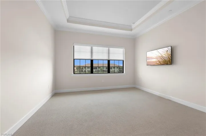 Empty room with a tray ceiling, baseboards, and crown molding