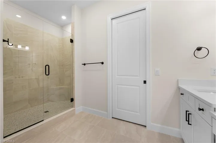 Bathroom with recessed lighting, vanity, baseboards, and a shower stall