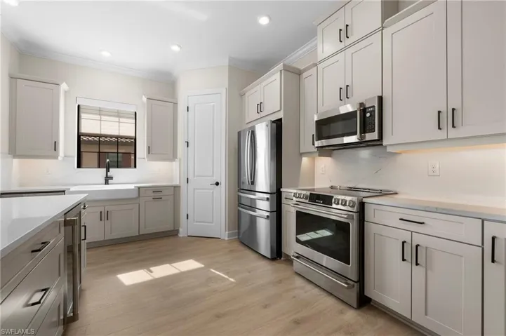 Kitchen featuring light countertops, a sink, stainless steel appliances, and crown molding