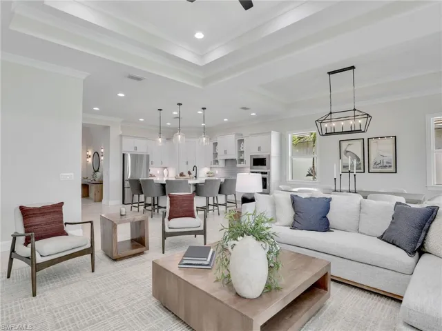 Living room featuring crown molding, recessed lighting, a raised ceiling, and ceiling fan