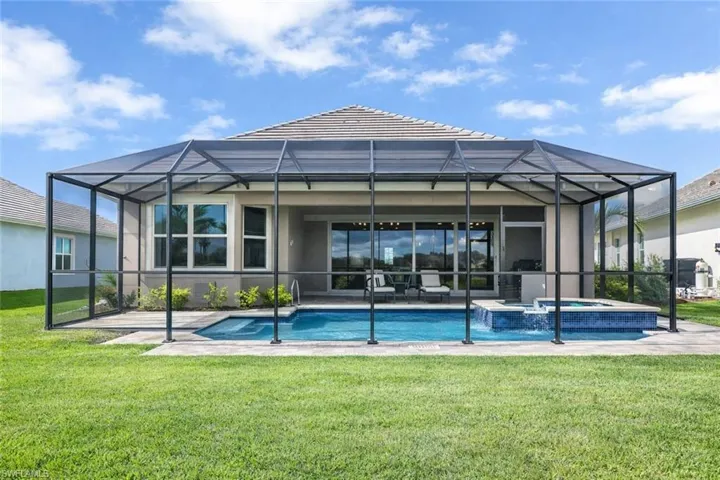 Back of house featuring a sunroom, a yard, a patio area, and a pool with connected hot tub