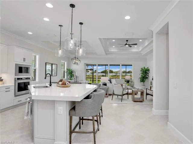 Kitchen featuring open floor plan, an island with sink, crown molding, oven, and a breakfast bar area