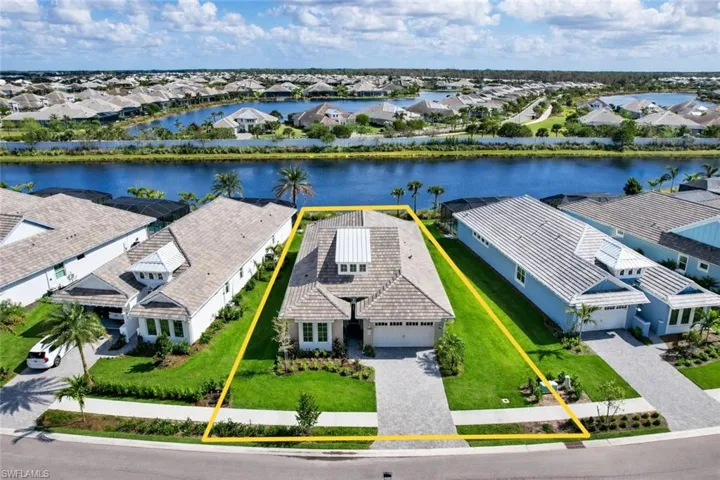 Aerial view of residential area with property boundaries highlighted and a nearby body of water