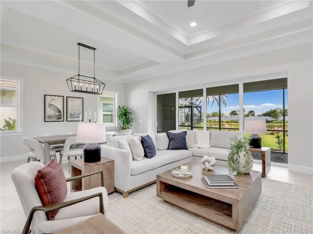 Living area with light tile patterned floors, a tray ceiling, and hanging lights