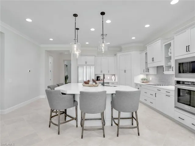 Kitchen featuring white cabinetry, built in appliances, backsplash, and crown molding