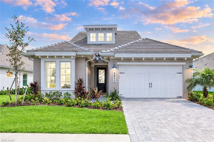 View of front of property featuring an attached garage, a tiled roof, driveway, and stucco siding