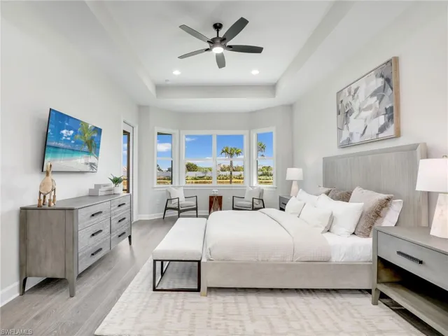 Bedroom featuring a ceiling fan, light wood-style flooring, recessed lighting, and a tray ceiling