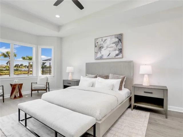 Bedroom with wood finished floors, ceiling fan, recessed lighting, and a tray ceiling