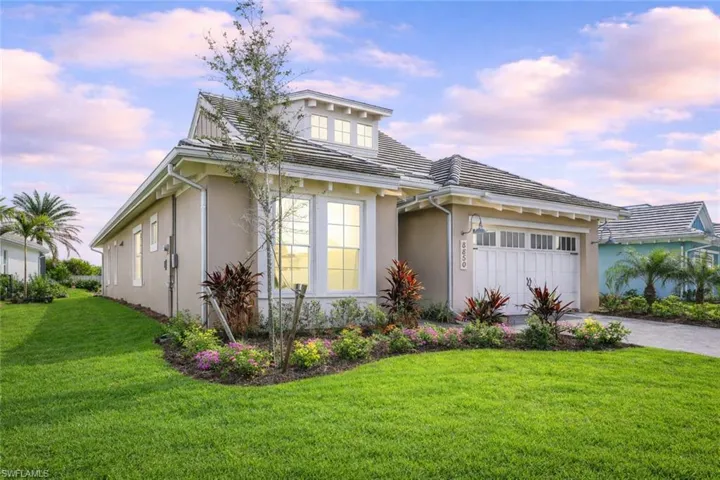 View of front of house with stucco siding, a yard, a garage, and driveway