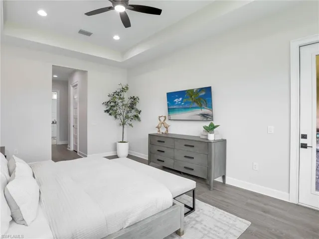 Bedroom with a raised ceiling, wood finished floors, ceiling fan, and recessed lighting