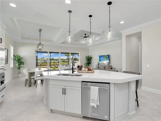 Kitchen with white cabinetry, stainless steel appliances, a center island with sink, a ceiling fan, and decorative light fixtures