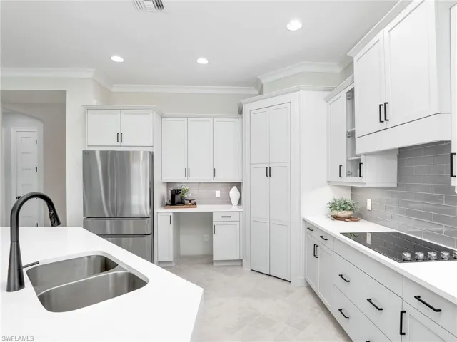 Kitchen with freestanding refrigerator, ornamental molding, black electric cooktop, recessed lighting, and backsplash