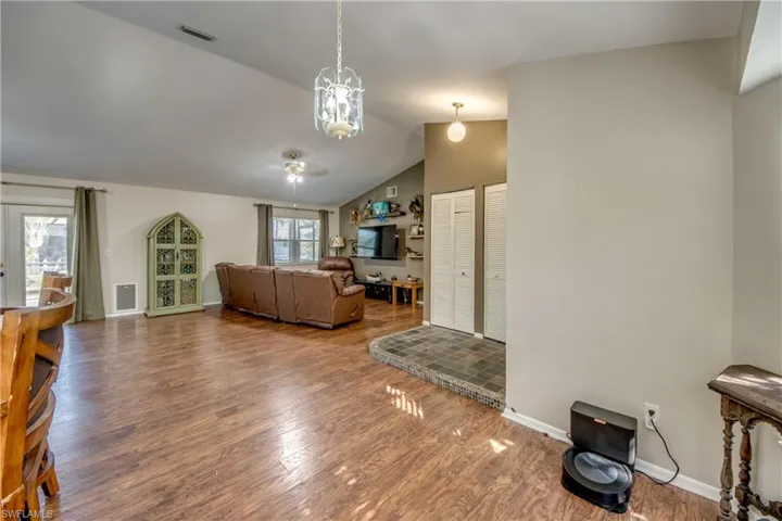 Living area featuring wood finished floors, lofted ceiling, a chandelier, baseboards, and a ceiling fan
