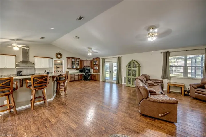 Living room with ceiling fan, healthy amount of natural light, dark wood-style floors, and lofted ceiling