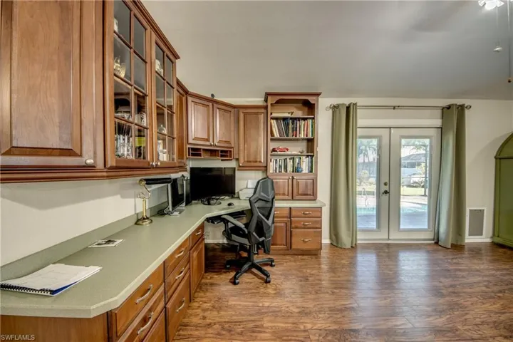 Office area featuring built in study area, french doors, and dark wood-style floors
